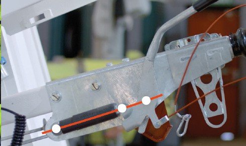 Fig. 68 — Under-chassis view showing the cable compensator bar correctly positioned perpendicular to the direction of travel (shown by orange annotation lines). The M8 adjuster nuts on each cable end must be locked in this position