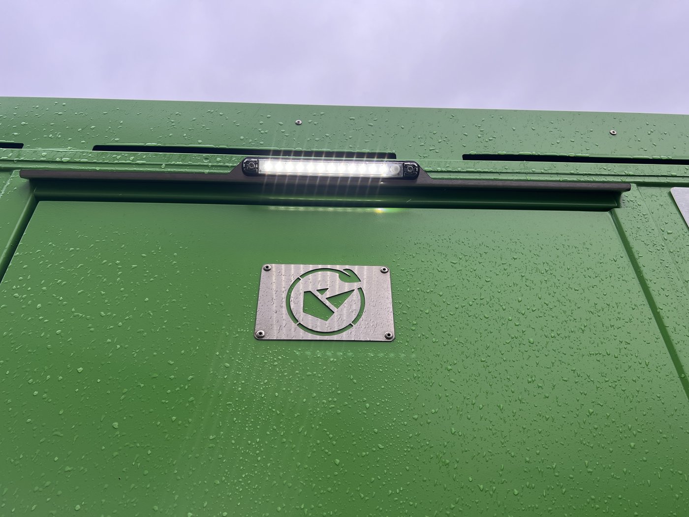 Fig. 8 — Exterior LED strip light above the access door, with the Boss Cabins stainless steel badge below. The LED bar is PIR-activated and operates in low-light conditions only