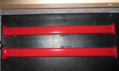 Fig. 54 — A pair of red hydraulic cylinder ram props. One prop is placed on each corner cylinder leg before working beneath the cabin. Secure with the supplied pin and R-clip