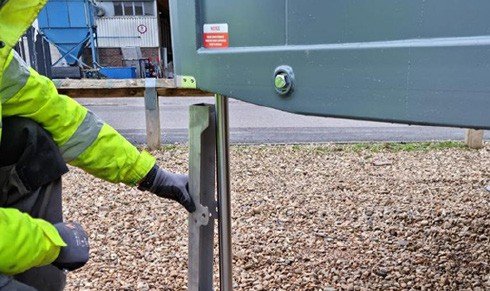 Fig. 55 — Technician fitting a ram prop onto the extended cylinder leg with the cabin raised. The prop slides over the cylinder and is secured with the pin and R-clip to prevent accidental lowering