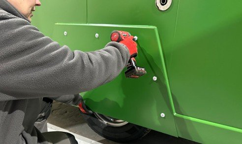 Fig. 57 — Removing the wheel guard panel on the Charge Space unit using an impact driver. All screws must be removed before the panel can be withdrawn from the side of the cabin