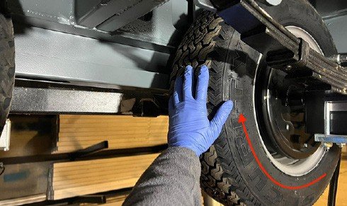 Fig. 62 — Checking that the wheel rotates freely in the forward direction (red arrow) after refitting. If the wheel does not turn freely, re-examine the brake adjustment before lowering the cabin